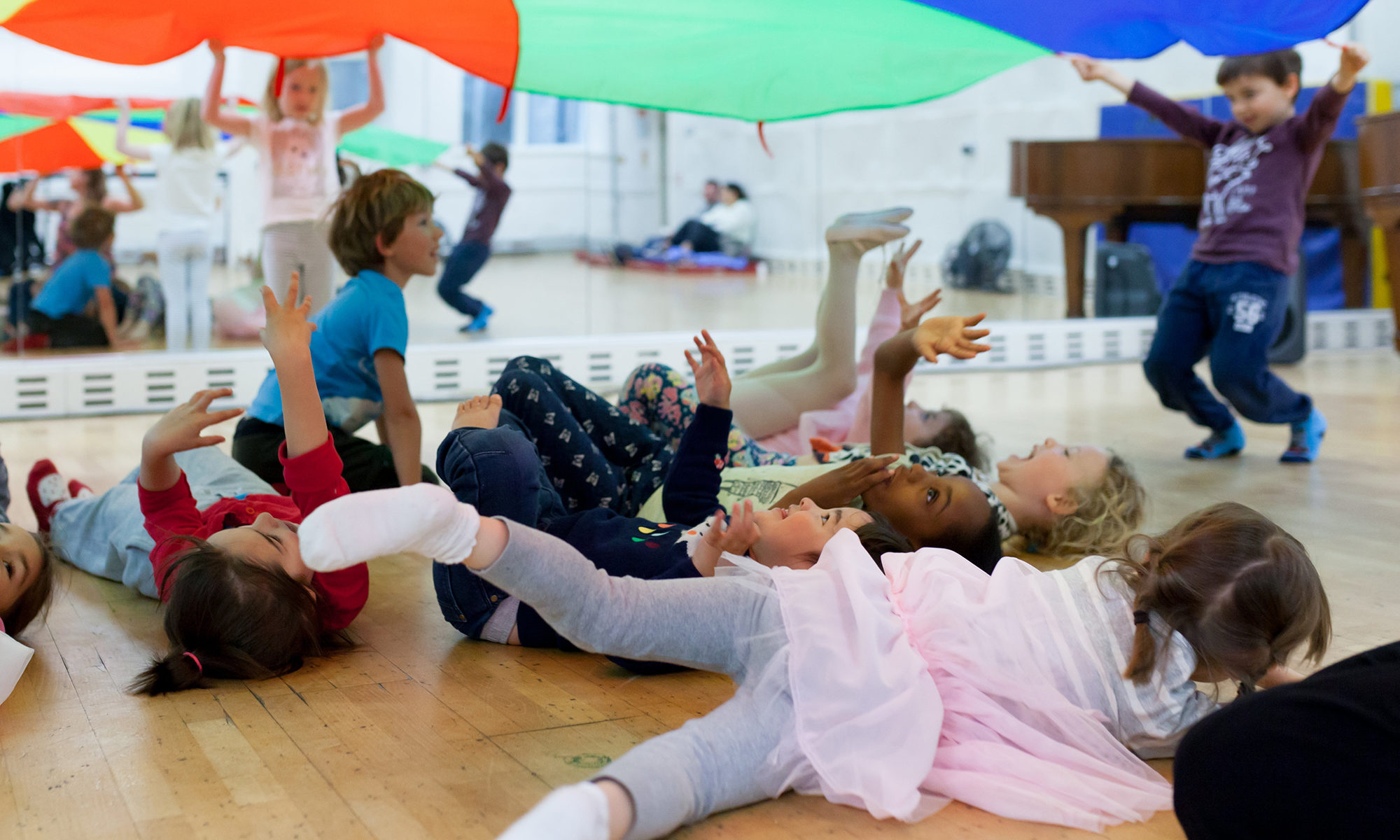 Children playing under a colourful parachute