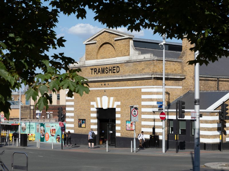 Looking through the trees at a brick building with the word 'Tramshed' above a large entrance way