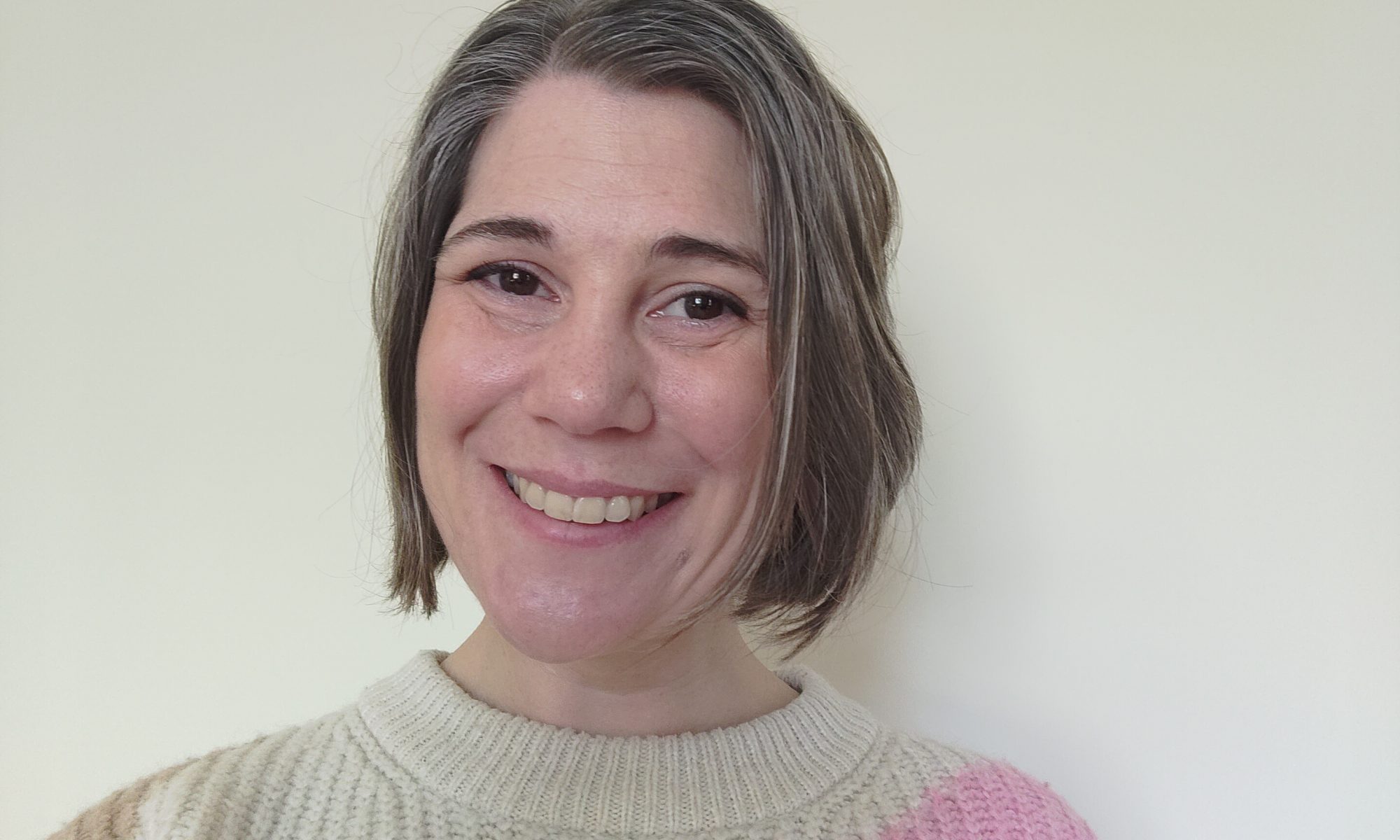 Photo of smiling woman. She is a white in her 30s with short hair.