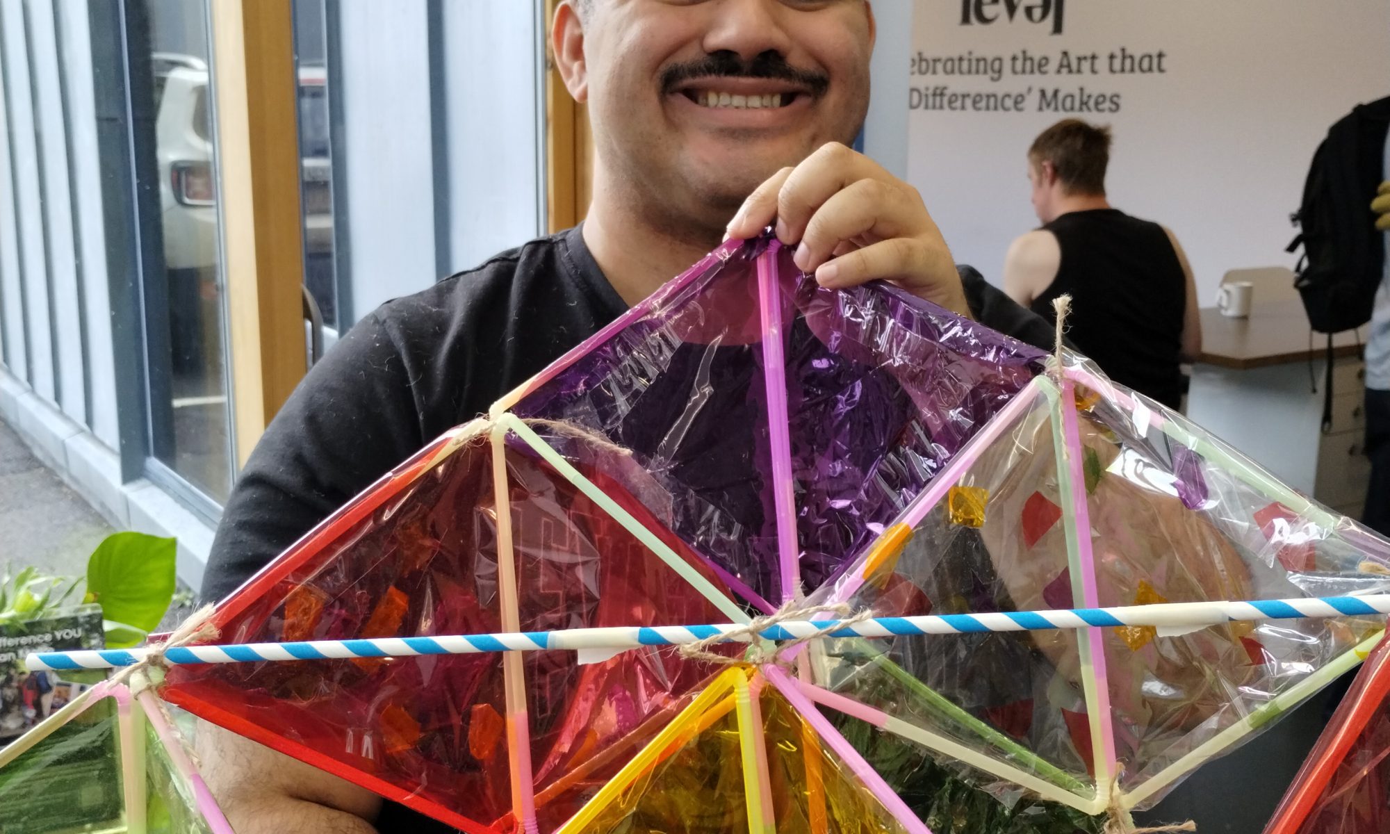 Person with a moustache smiling and holding a kite