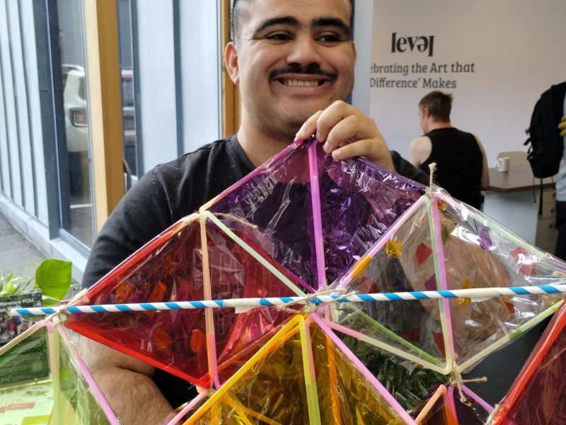 Person with a moustache smiling and holding a kite