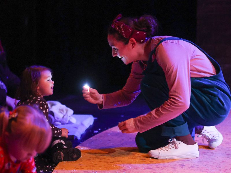 Adult holding a small light towards a child, and illuminating their face