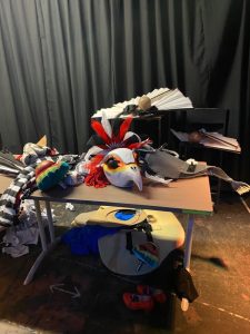 A bird's head puppet on a table with other paraphernalia from the show.