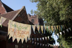 Bunting (created in community workshops with artist Clare Marsh) strung outdoors, with a large panel reading 'Freedom Road'