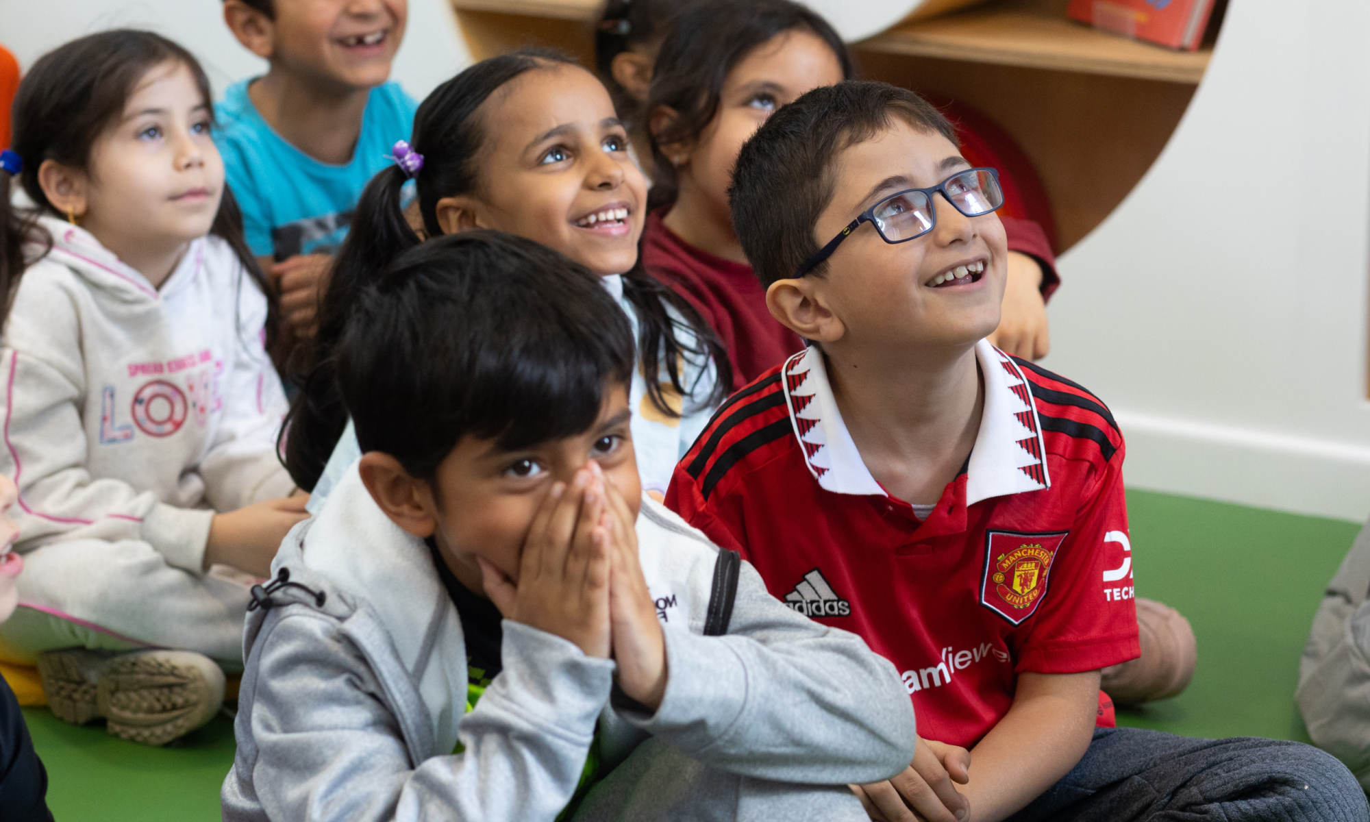 Children looking happy and delighted as they watch something (out of shot) at Z-Arts