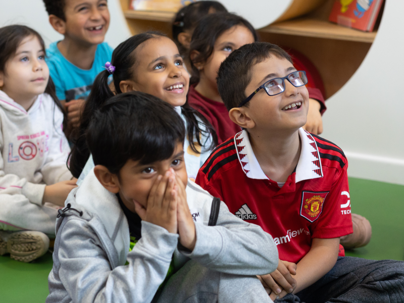 Children looking happy and delighted as they watch something (out of shot) at Z-Arts