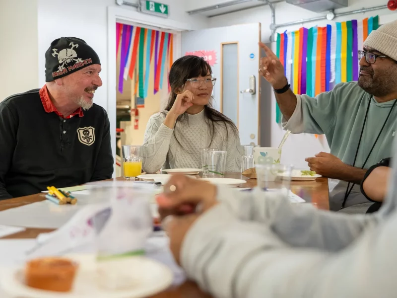 People smiling as they sit around a table and talk